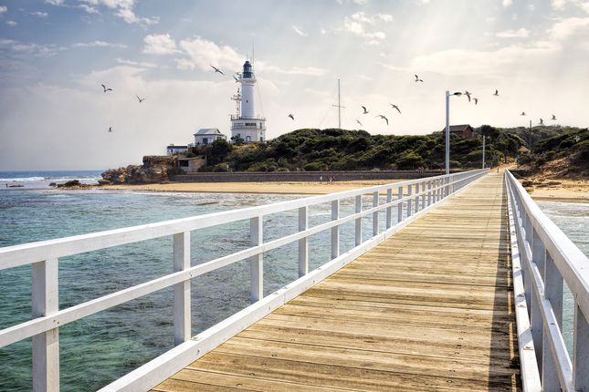 View of Point Lonsdale Lighthouse and jetty with seagulls in sky at the Bellarine Peninsula in Victoria